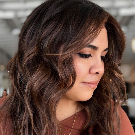 Model with chocolate brown highlights on wavy brunette hair.