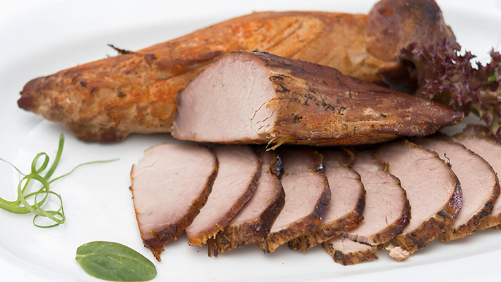 Roasted pork tenderloin, sliced on serving dish.