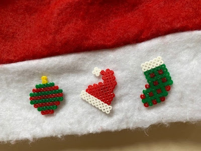 Mini Hama bead Christmas pin badges on a Santa hat