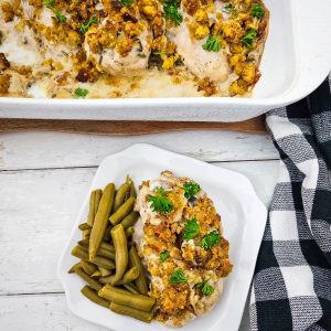 Close-up of a golden brown Chicken and Stuffing Bake, with a portion served on a white plate with green beans, garnished with parsley.