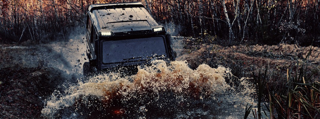 A stock photo of a four-wheel-drive vehicle going through a mud puddle.