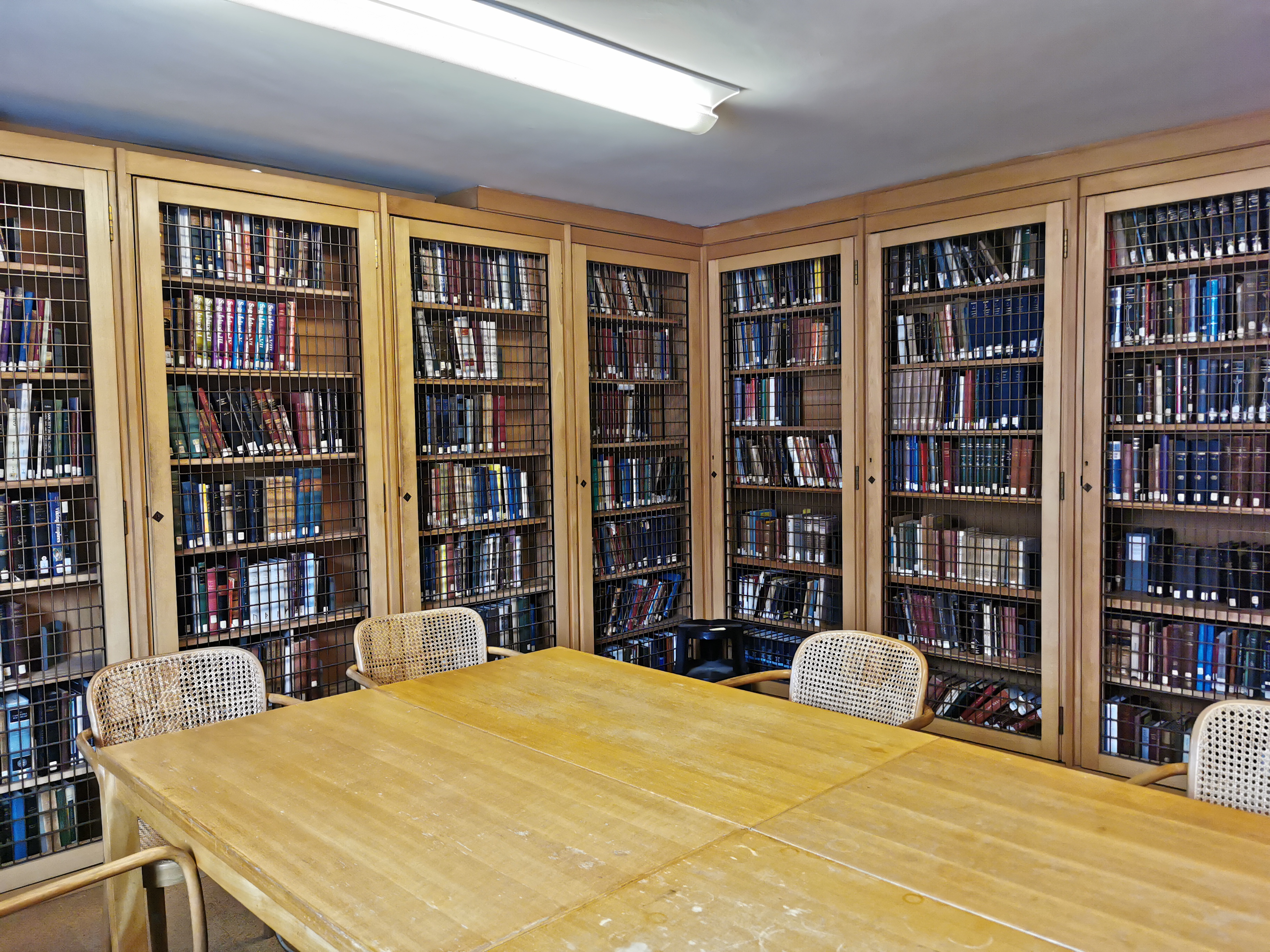 In the background, there is the wooden cages in the Turville-Petre Room with our Old Icelandic-Norse collections behind them. A large wooden study table is in the foreground surrounded by brown wicker chairs.