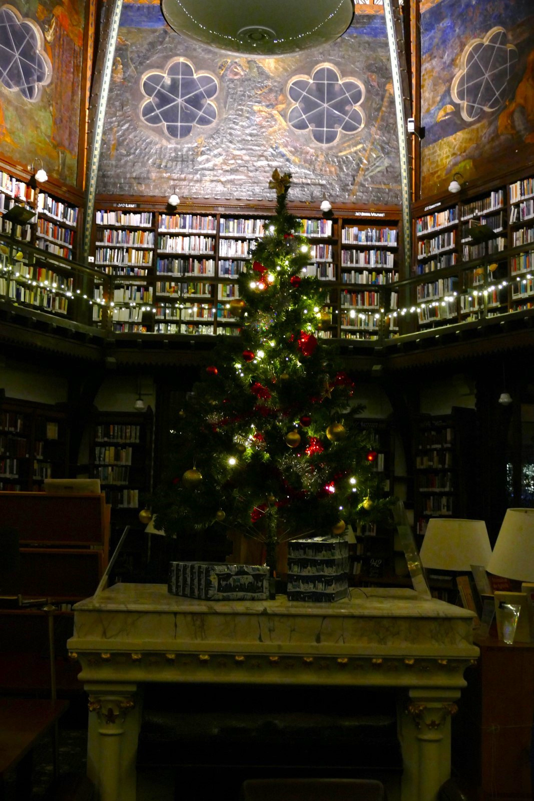 A Christmas tree stands on a marble table in the Union Society Old Library. There are bookcases and decorative walls visible in the background.