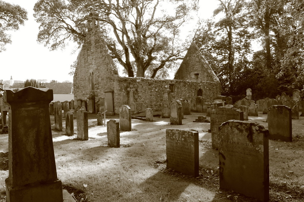 A sepia picture of the remains of the Alloway Auld Kirk, graves in the foreground and church in the back