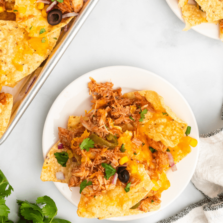 bbq chicken nachos on white plates with cilantro garnish