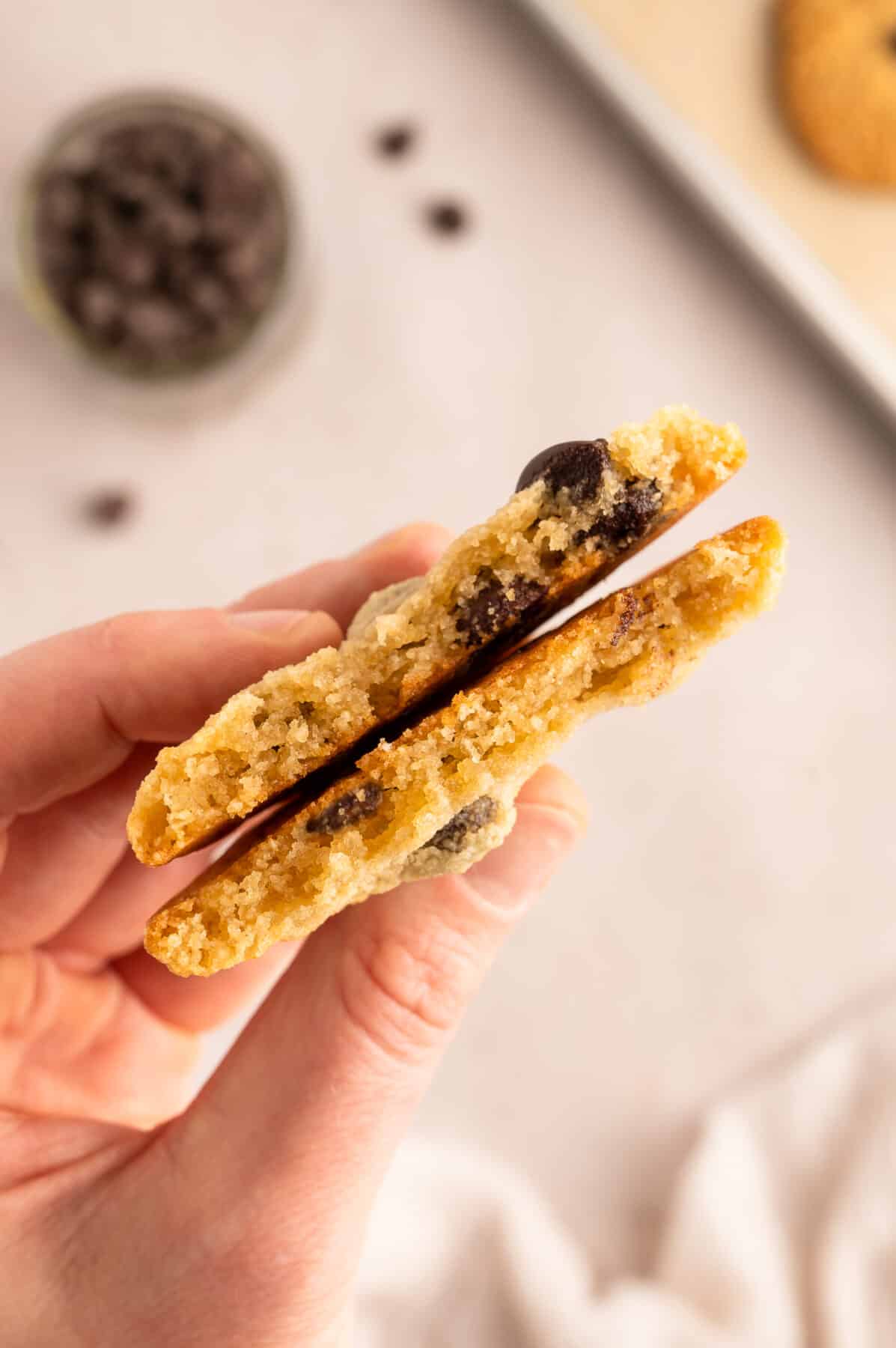 holding an almond flour cookie broken in half to see the soft center of the cookie.