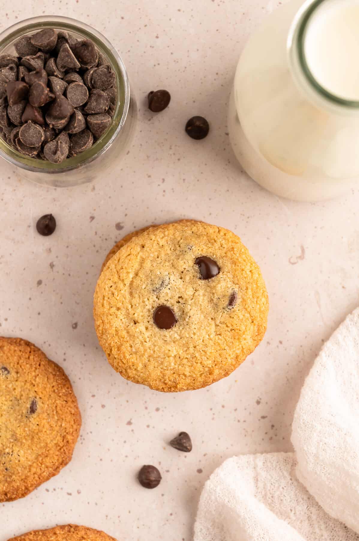 stack of chocolate chip cookies with a glass of milk to the side. 