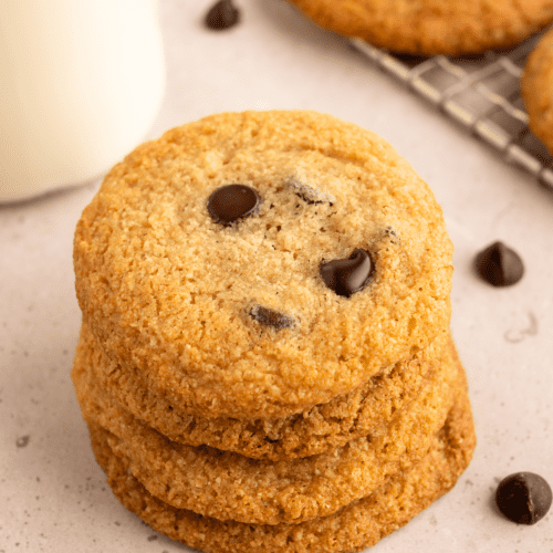 stack of almond flour chocolate chip cookies with glass of milk behind it.