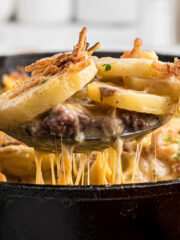 Ground Beef Casserole in a cast iron skillet with a spoon taking out a big scoop.