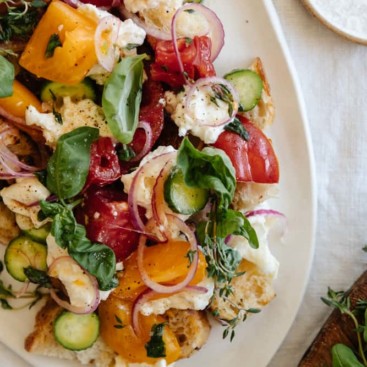 panzanella salad on a white platter on a linen tablecloth