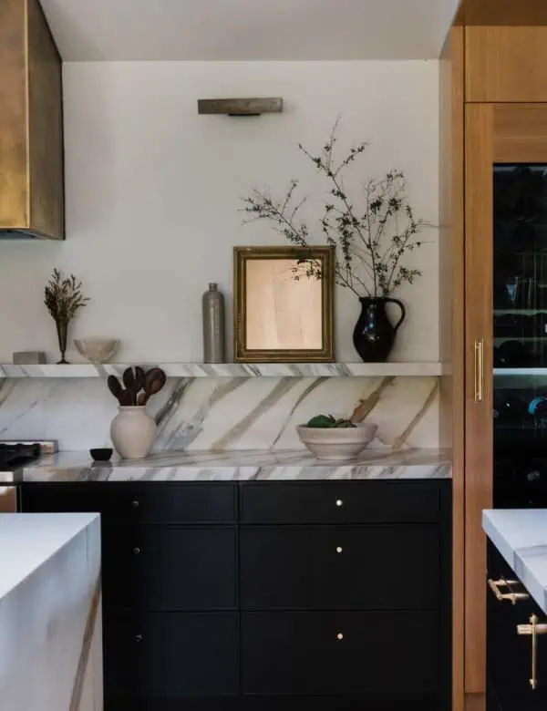 kitchen with bold marble countertop and backsplash created into a small shelf with art and decor on the shelf and countertop