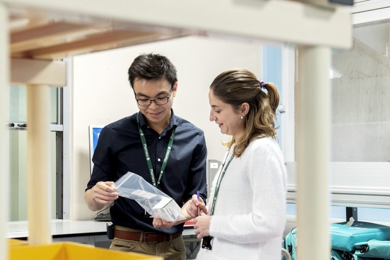 Pharmacy staff looking at medication in a sealed bag.