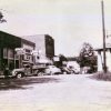 street scene with gazebo on one side and cars parked in front of stores and businesses on the other