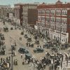 Crowded city street with multistory buildings cars and trolley car