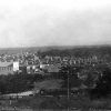 Town viewed from farmed hillside with multistory businesses in foreground and neighborhoods in distance