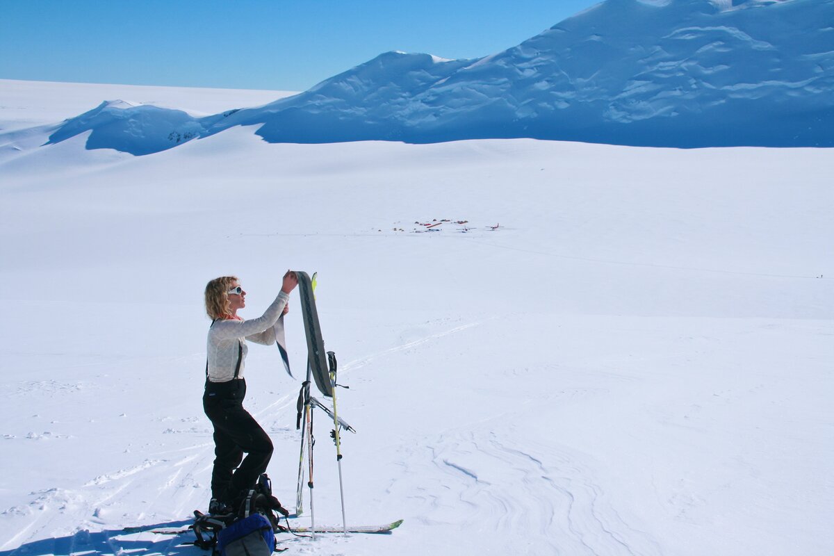 Skier removes skins from skis at top of tour