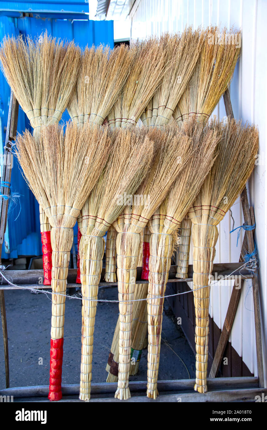 Rows of handmade brooms in a rustic market close-up Stock Photo