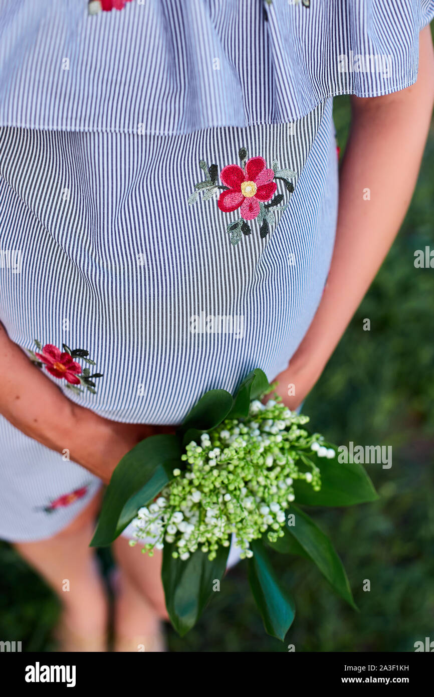 Pregnant woman holding her belly and flower, outdoor. Pregnancy ...