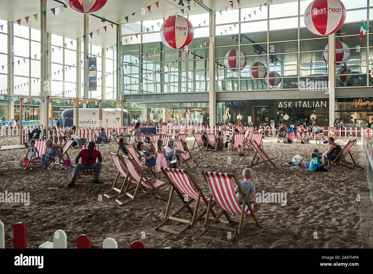 In the centre of Milton Keynes shopping mall deckchairs and sand provided to make a seaside effect while shopping Stock Photo