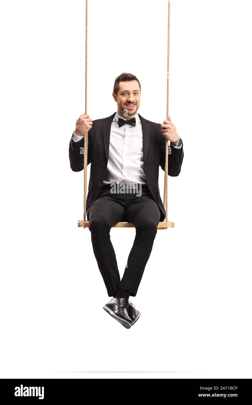 Elegant man in a suit sitting on a wooden swing isolated on white background Stock Photo