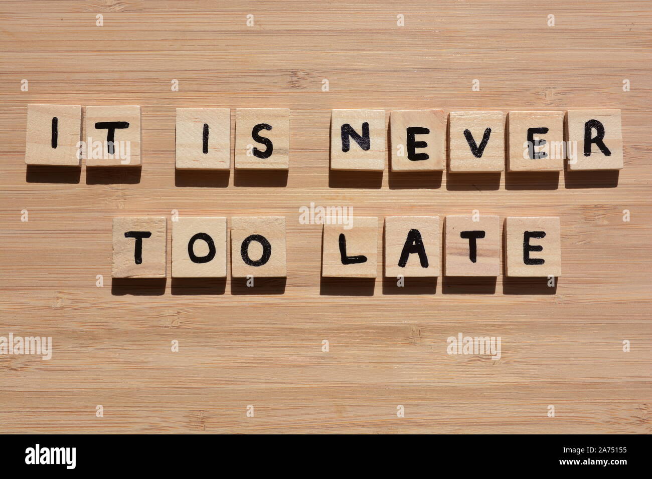 It Is Never Too Late. Motivational words in 3d wooden alphabet letters on a bamboo wood background Stock Photo