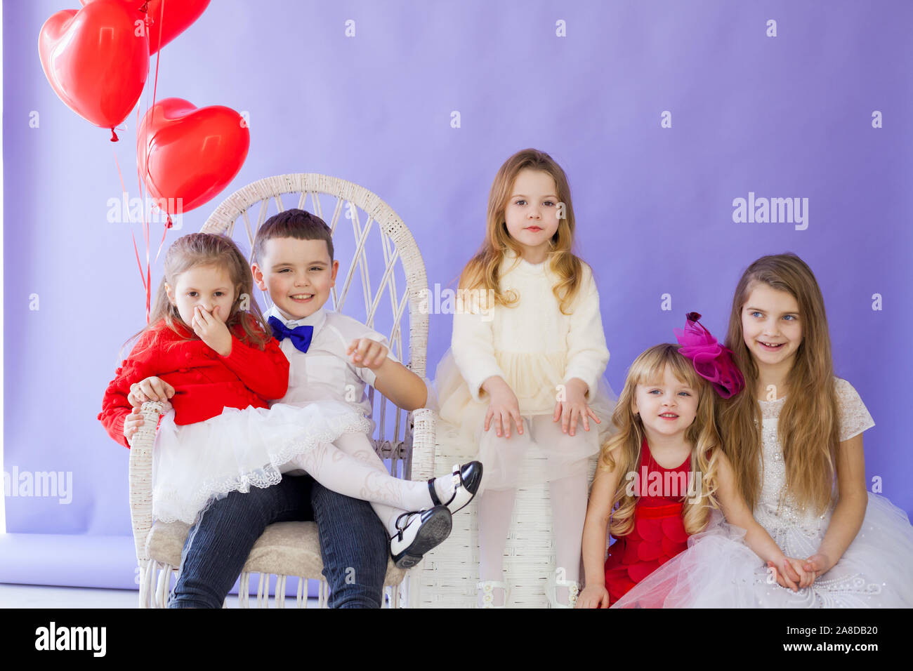 Boy and girls with red heart-shaped balloons on birthday party Stock Photo