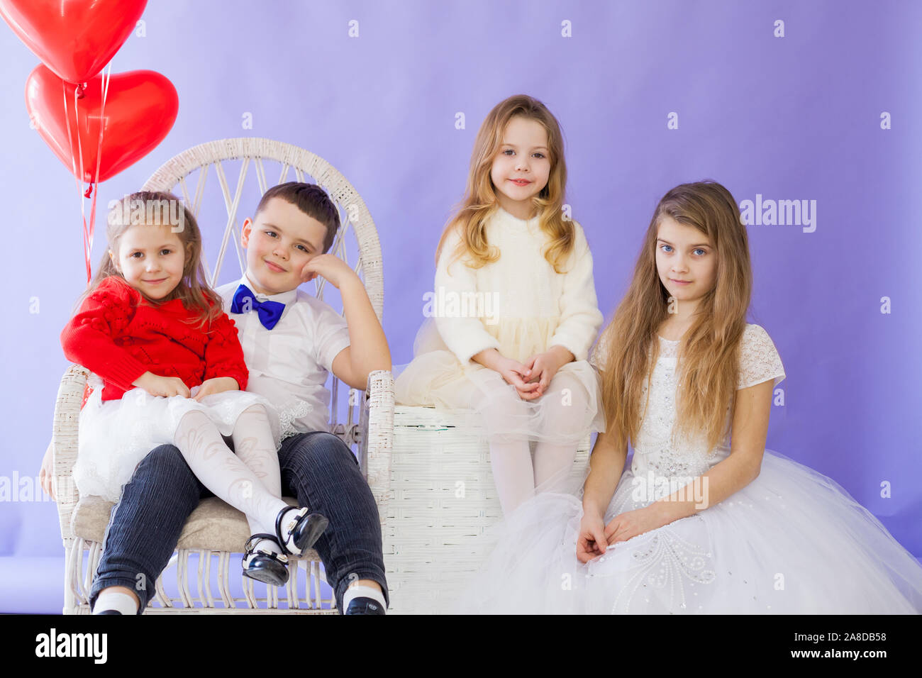 Boy and girls with red heart-shaped balloons on birthday party Stock Photo