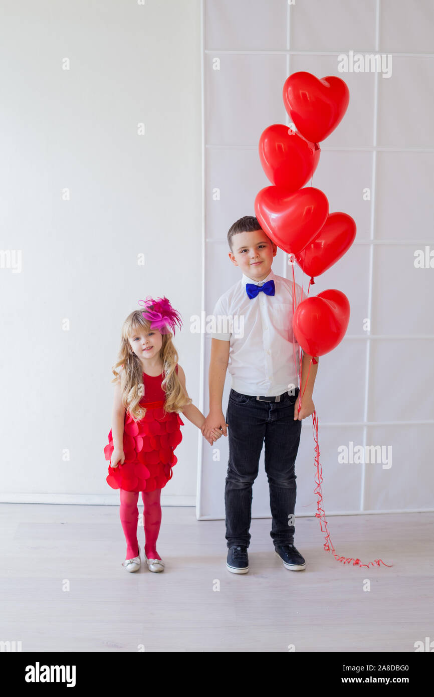 Boy and girl with red heart-shaped balloons on birthday party Stock Photo