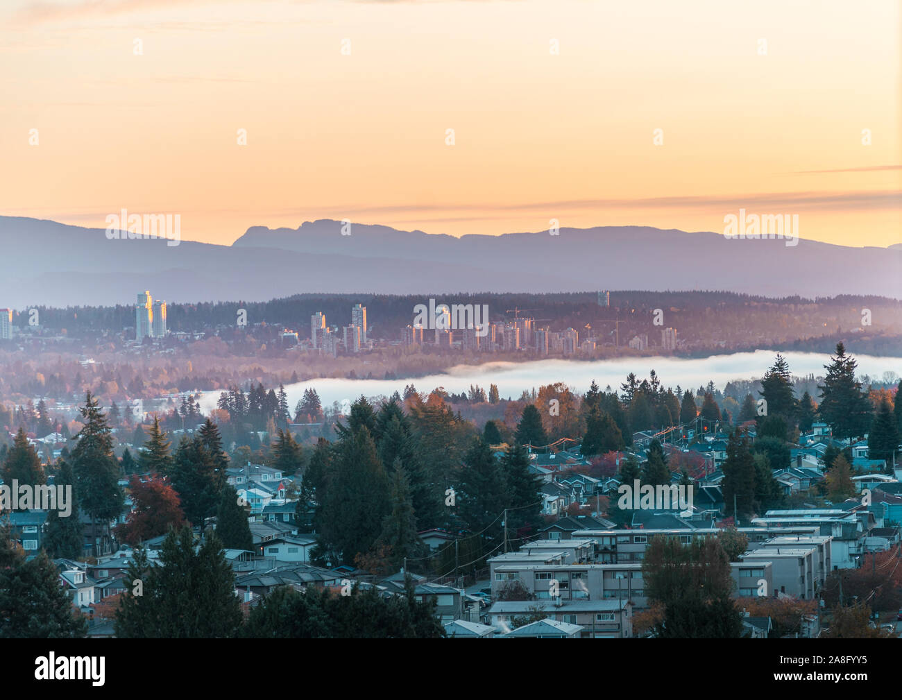 Autumn sunrise over Burnaby with scenic mountains backdrop and fog above Deer lake Stock Photo