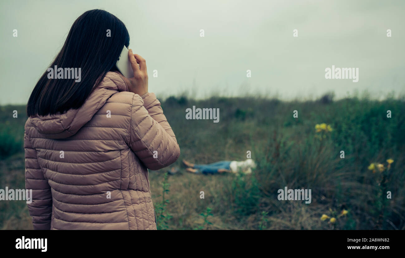 Woman calling emergency services for a dead body Stock Photo