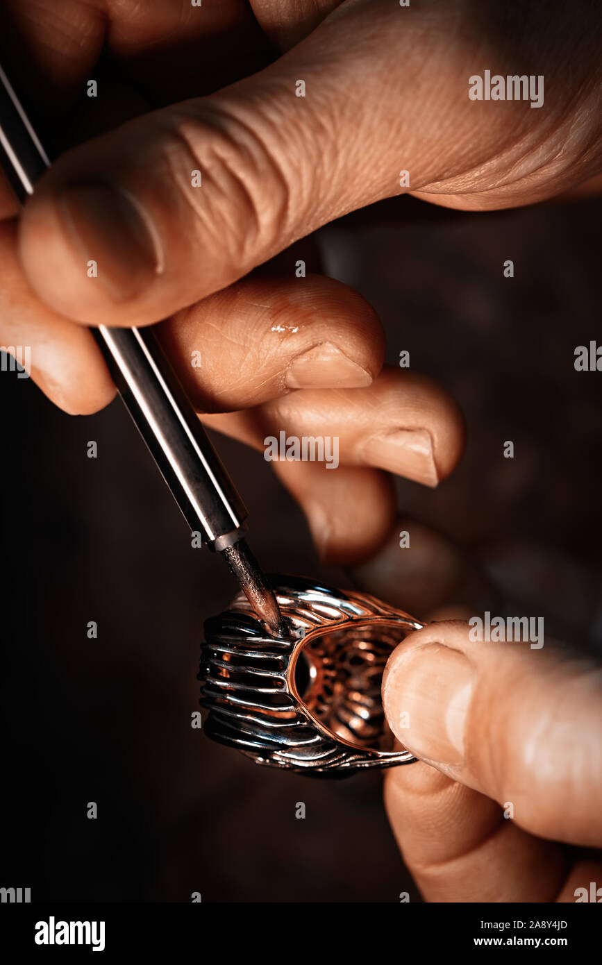 A jeweler is treating a rhodium the gold ring. Stock Photo