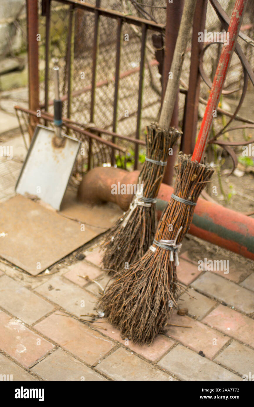 Two old handmade brooms and a scoop in the yard Stock Photo