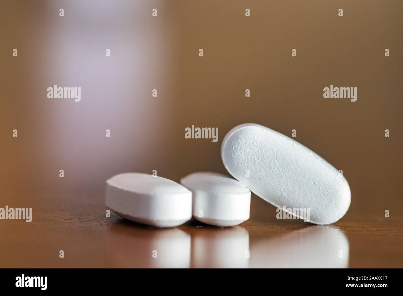 Close -up of three pills with an oval shape on a table, selective focus. Stock Photo