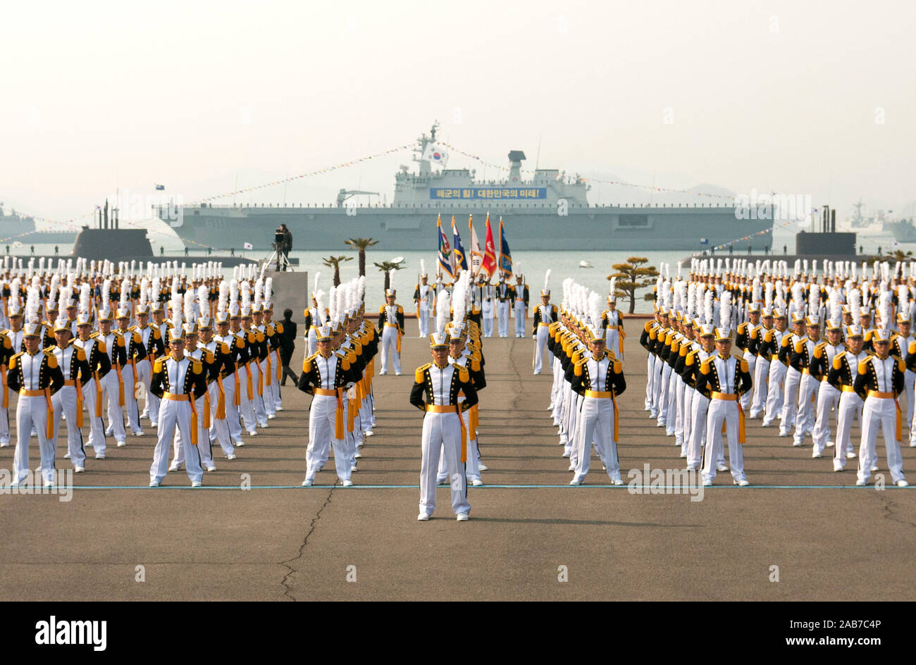 JINHAE, Republic of Korea (Feb. 22, 2013) Midshipmen at the Republic of Korea (ROK) Naval Academy stand in formation at parade rest with ROK Navy ships and submarines behind them minutes before the commencement of their graduation ceremony. Stock Photo