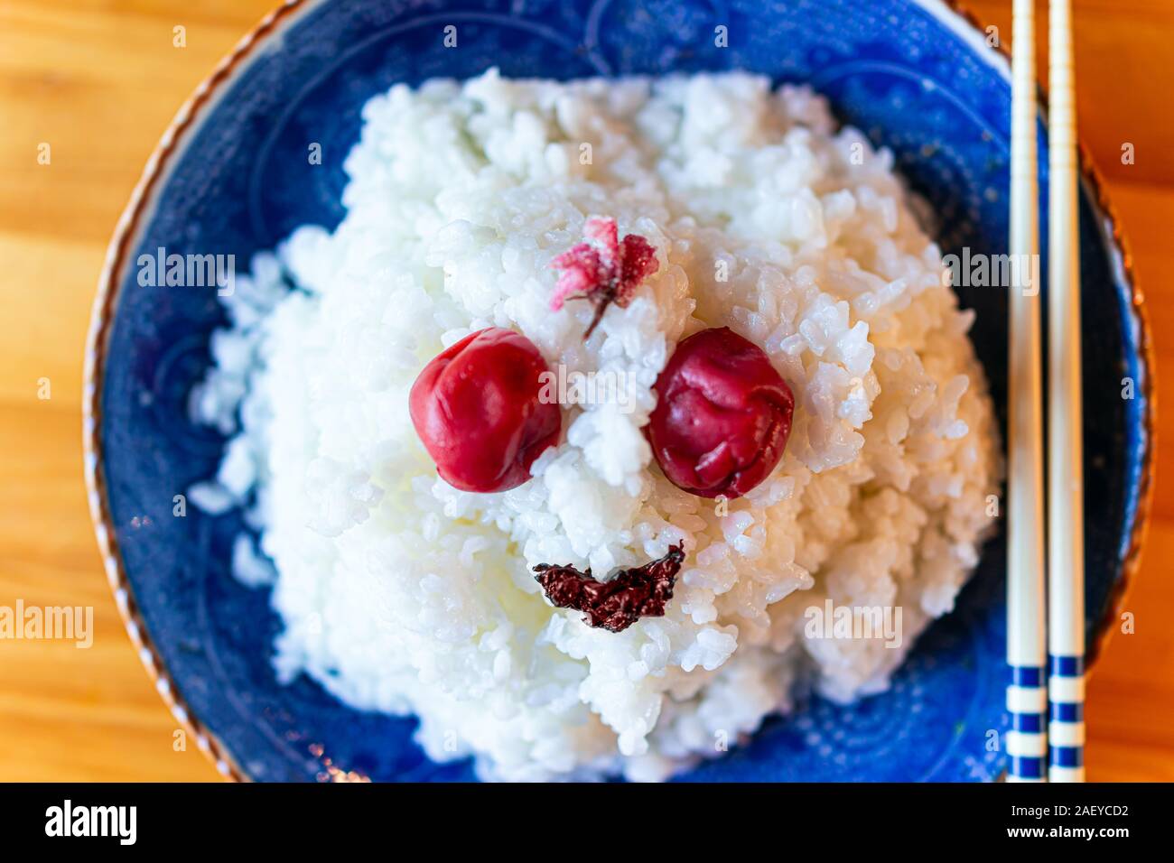 Flat top view of japanese ceramic plate in restaurant or home with wooden table and vegetable dish with plain white rice and shiso, umeboshi, chopstic Stock Photo