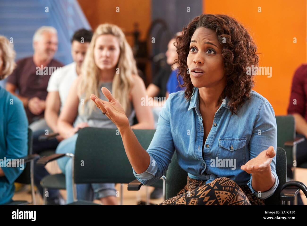 Frustrated Woman Asking Question At Group Neighborhood Meeting In Community Center Stock Photo