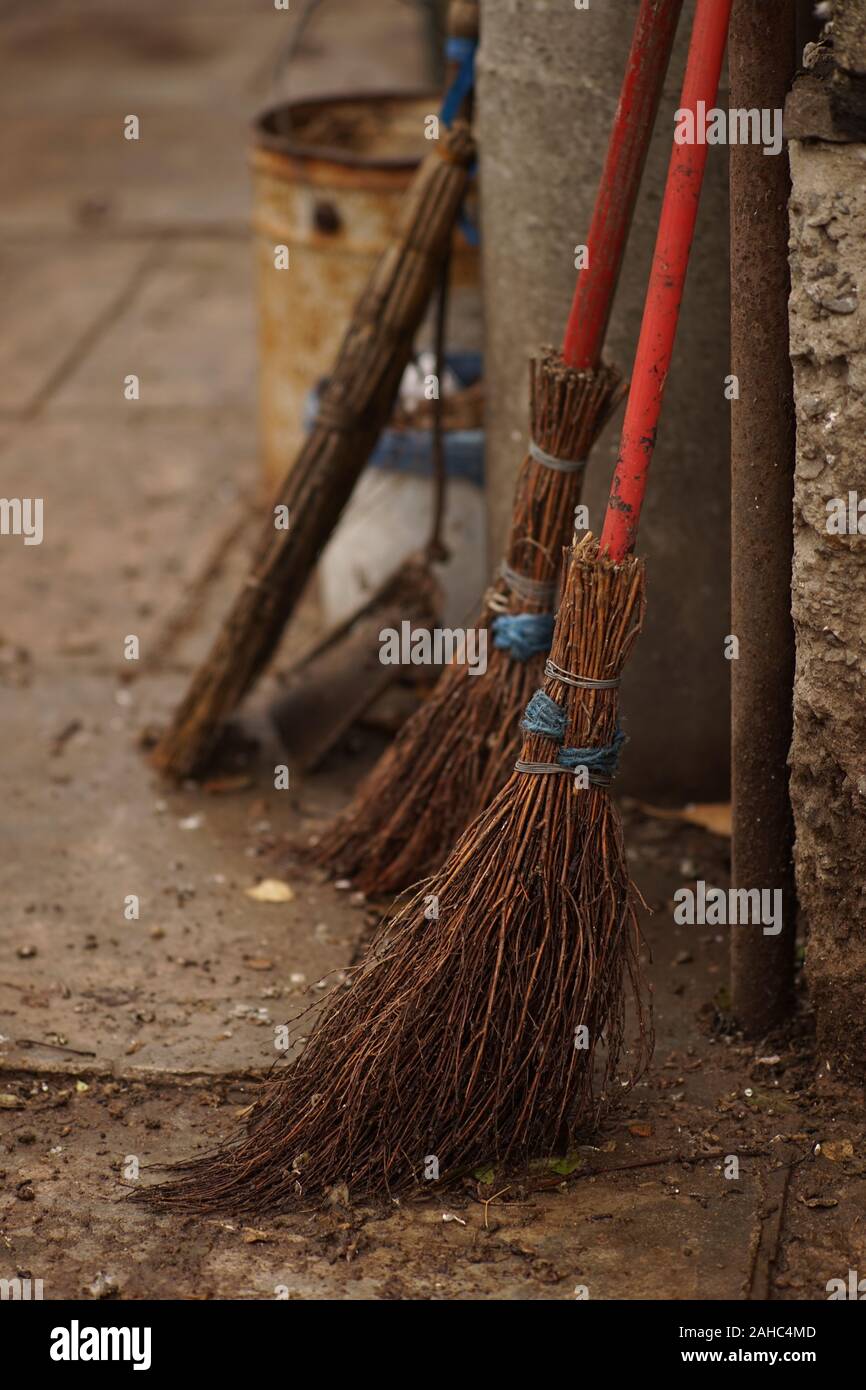 Set of old wicker knitted brooms in a wet rural yard. Stock Photo