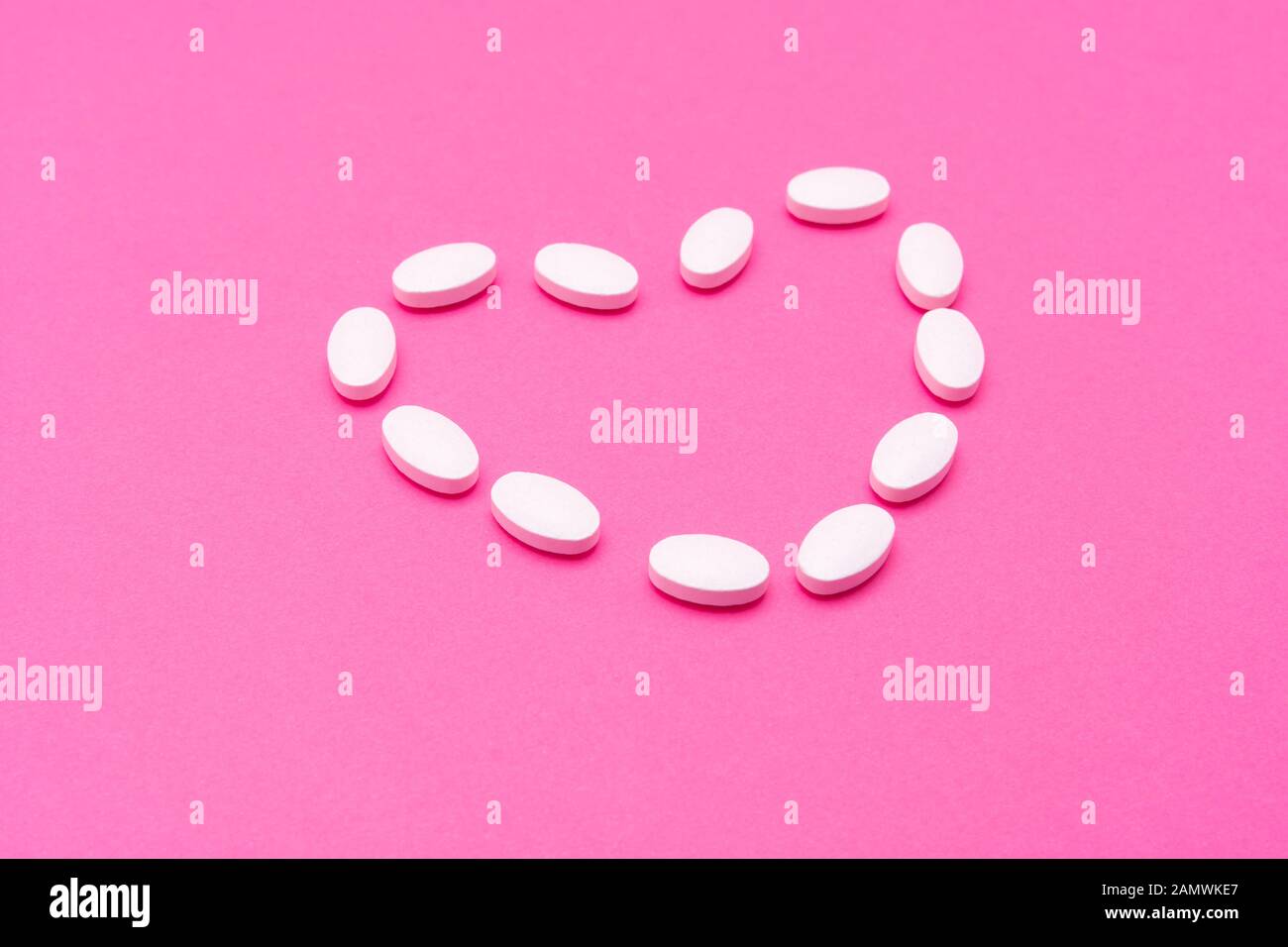 White oval pills lie on pink background. Copy space, macro Stock Photo