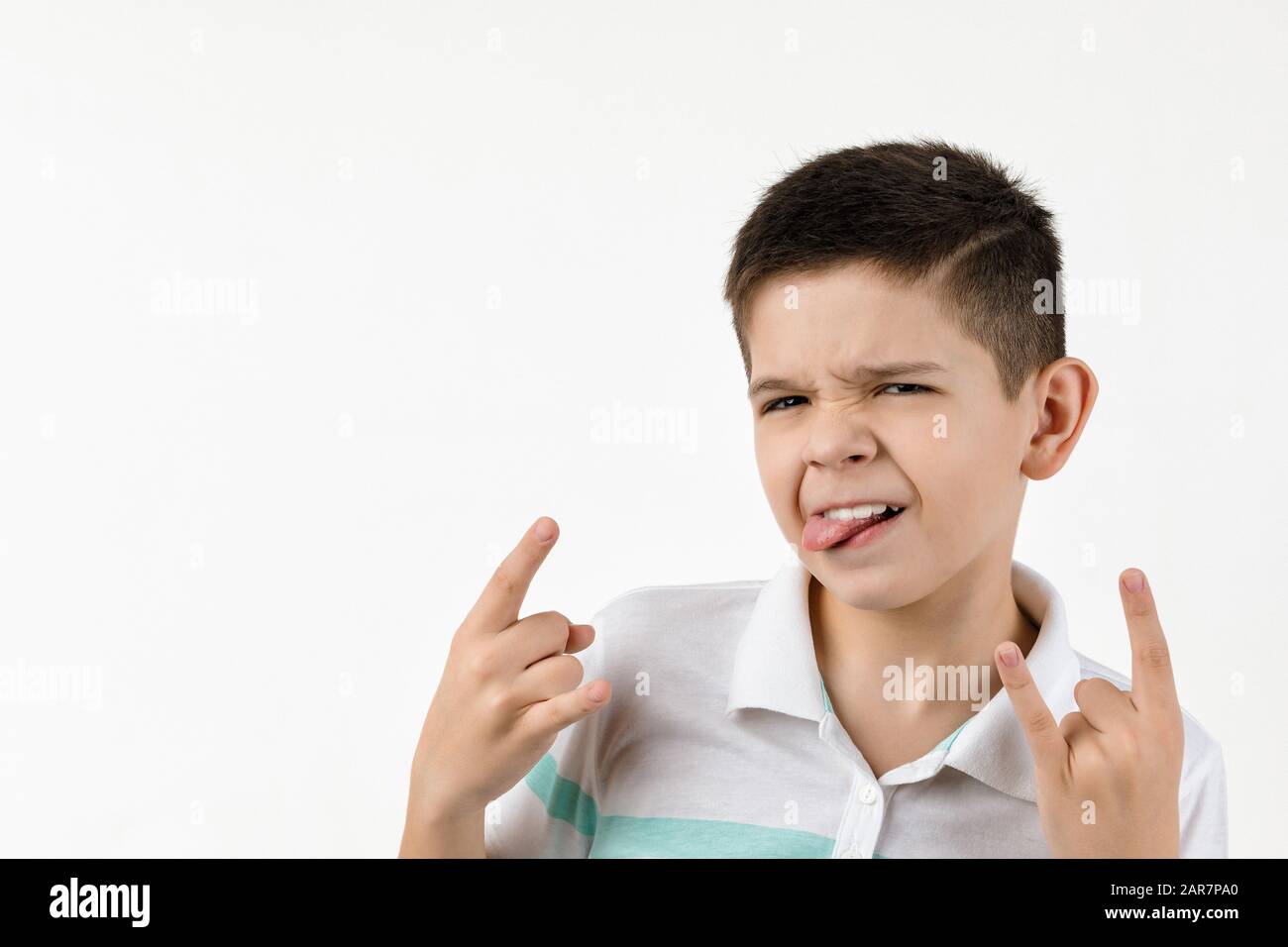 Cute little child boy in striped t-shirt making Rock gesture on white background. Stock Photo