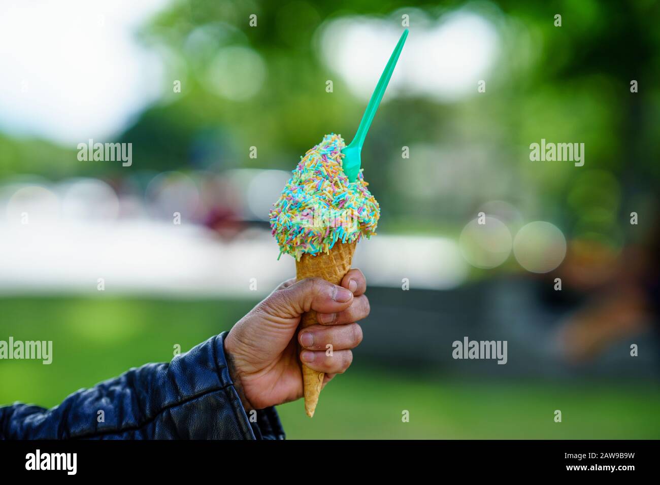 Man holding ice cream cone. Detail of ice cream with Rainbow Sprinkles in hand Stock Photo