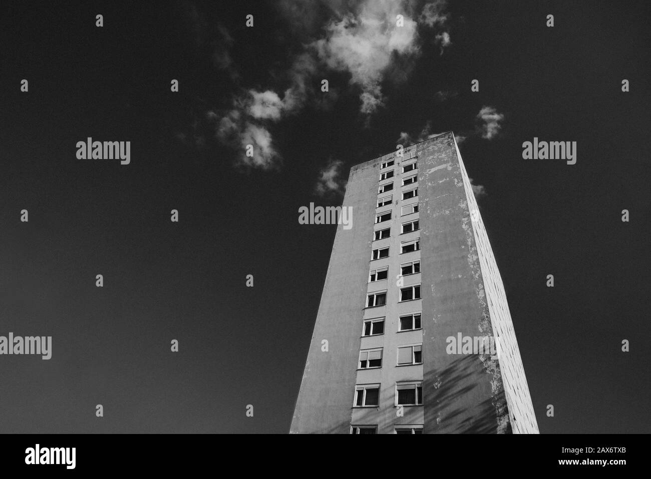 Low angle shot of a tall building against a  cloudy sky in black and white Stock Photo