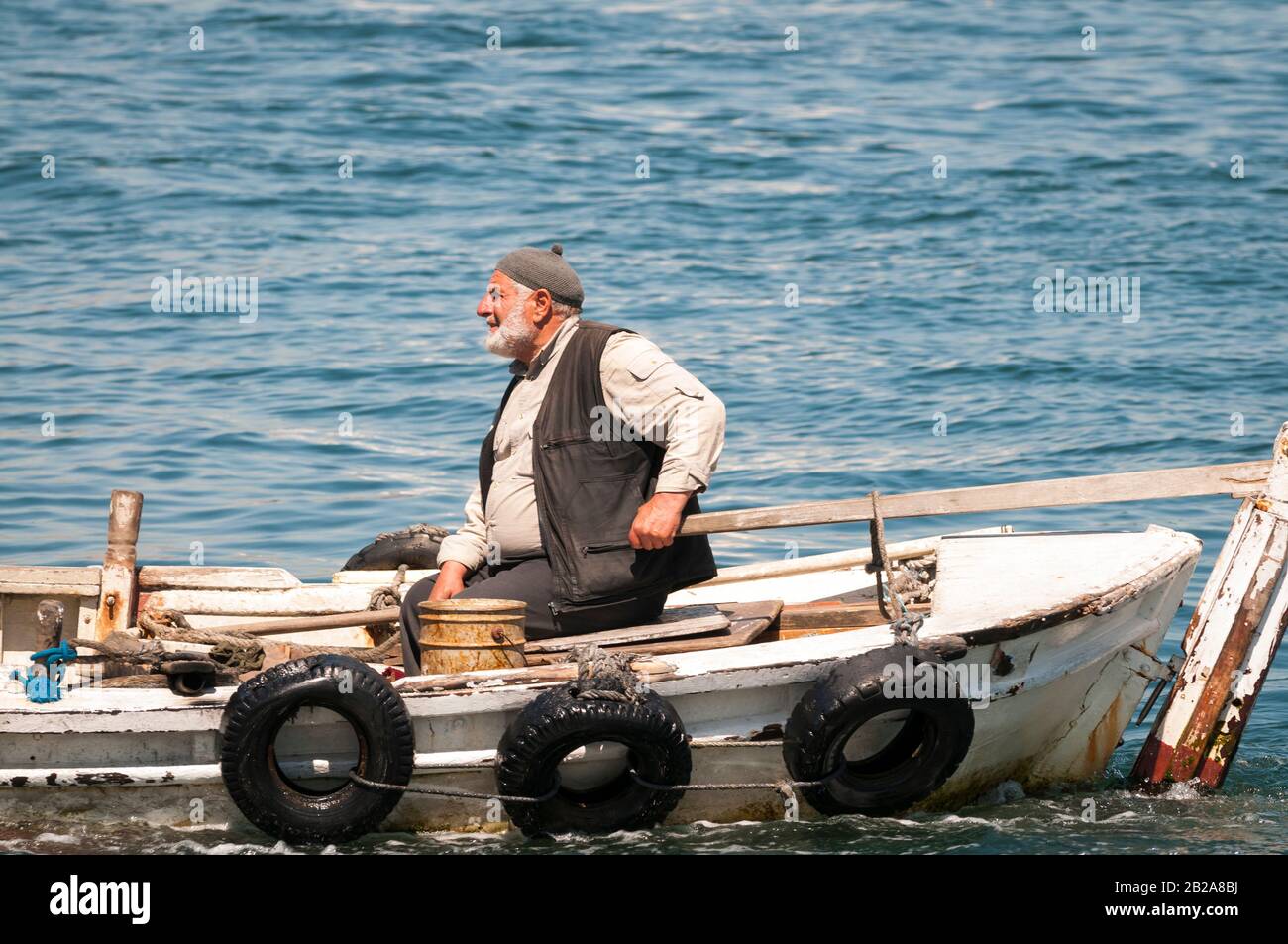 ISTANBUL - MAY 7, 2010: A Turkish man steers a traditional wooden boat on the Golden Horn of the Bosporus Strait. Stock Photo