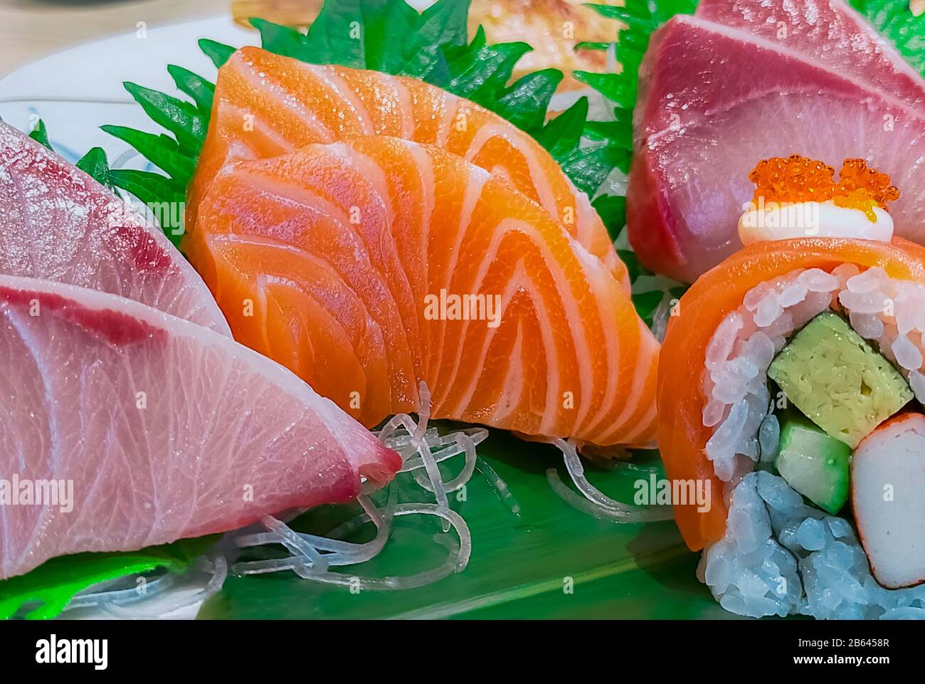 Japanese food set served on white plate. Salmon sushi and sashimi on restaurant table. Fresh raw fish meat sliced and Japan vinegared rice rolls with Stock Photo