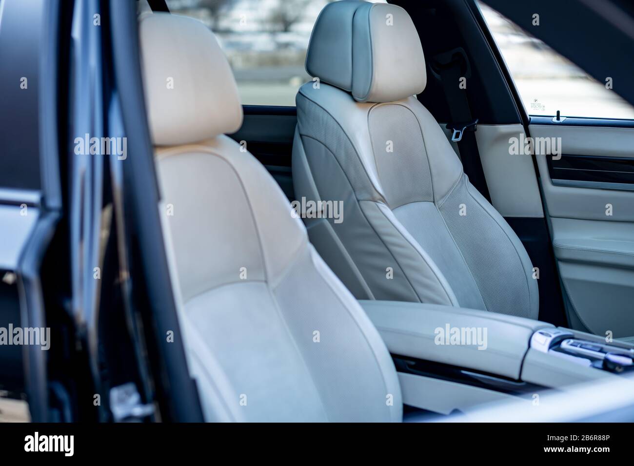 White leather interior seats and dashboard inside a luxurious BMW 750d black limousine with 381hp, hi-tech comfort equipment. M Package and Individual Stock Photo