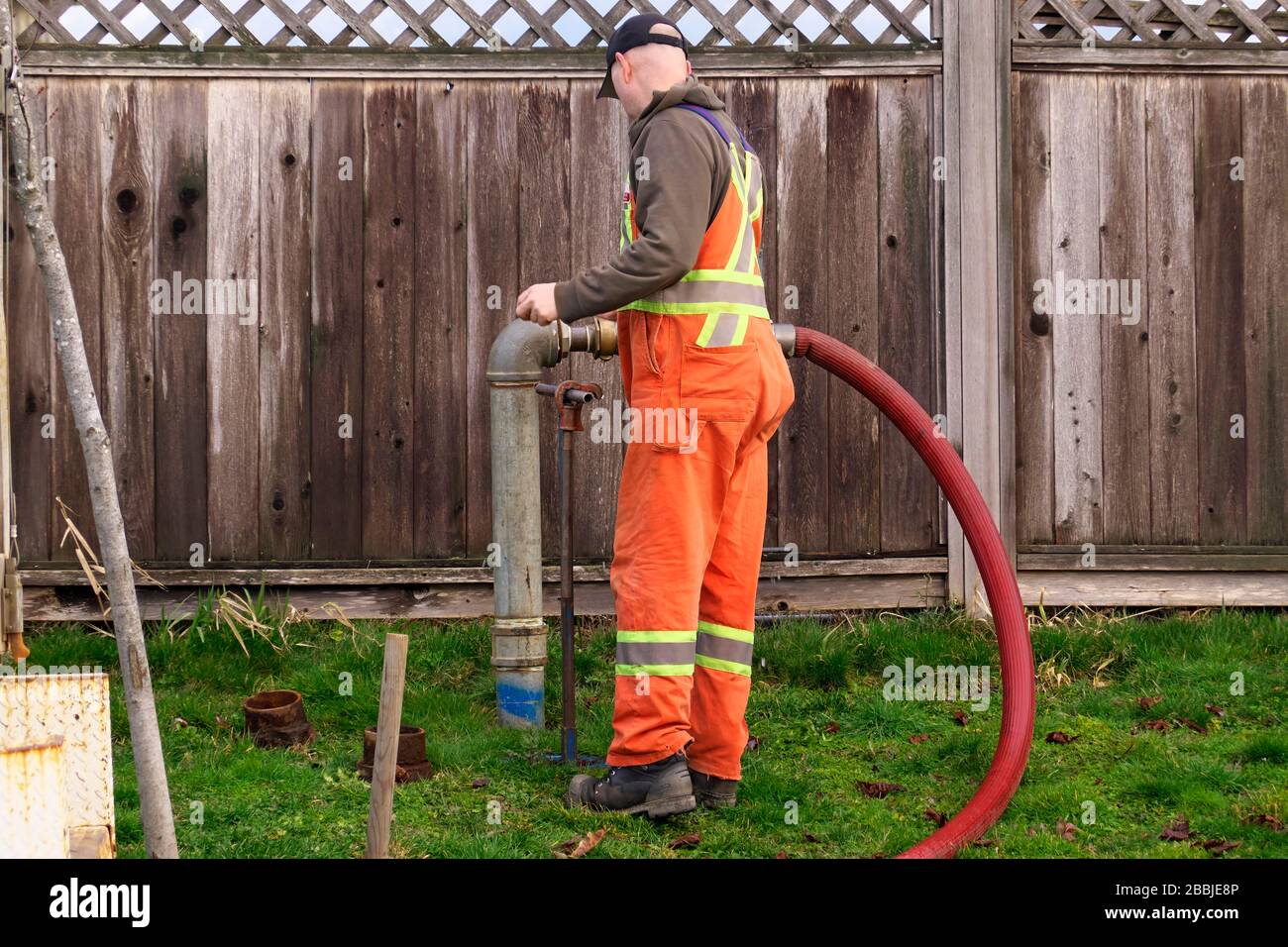 A municipal worker in orange coveralls doing maintenance in Pitt Meadows, B. C., Canada.  Stock photo. Stock Photo