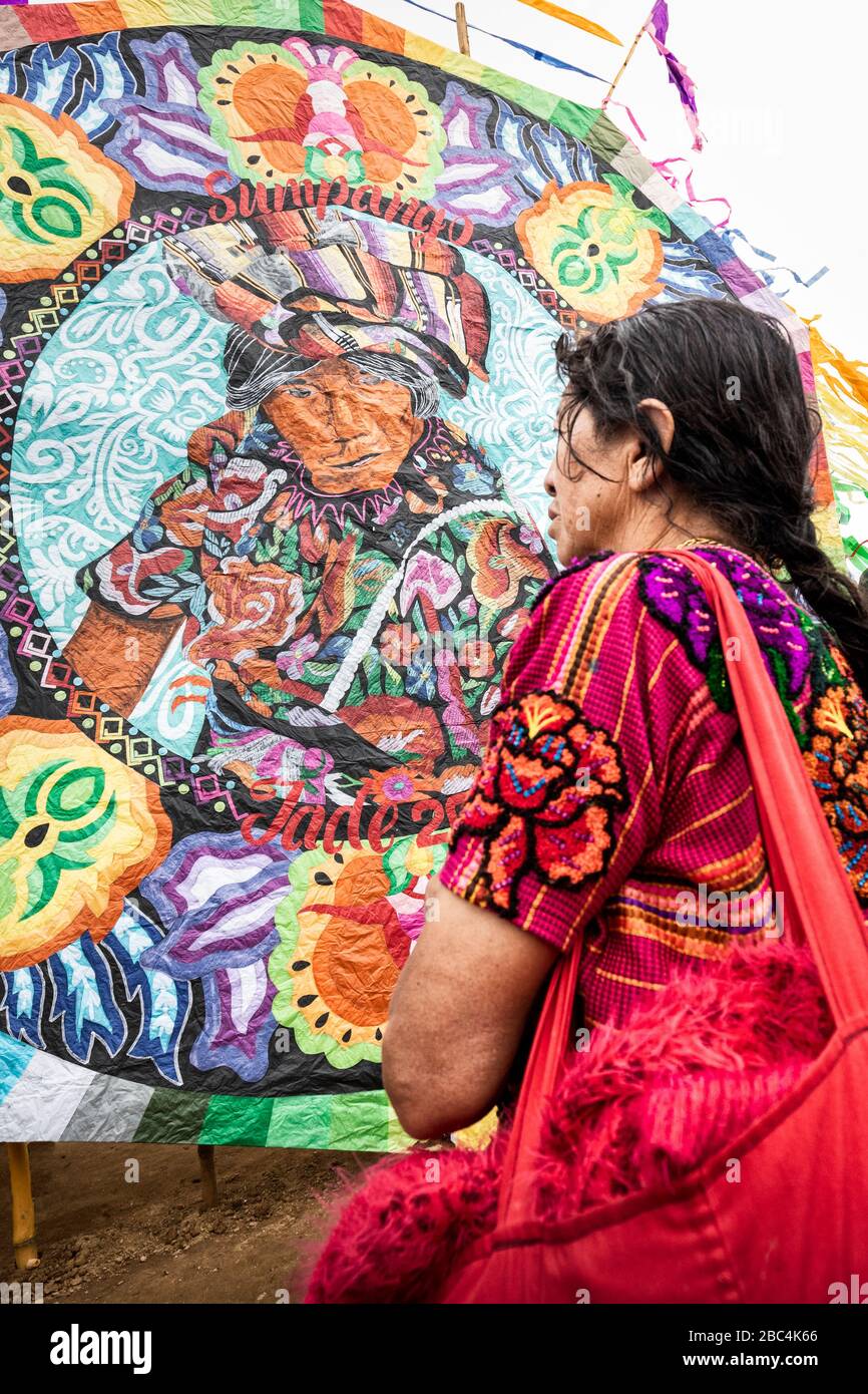 Figure on a large barrilete seemingly gazes down at a woman at the Sumpango Kite Festival on Day of the Dead in Guatemala. Stock Photo