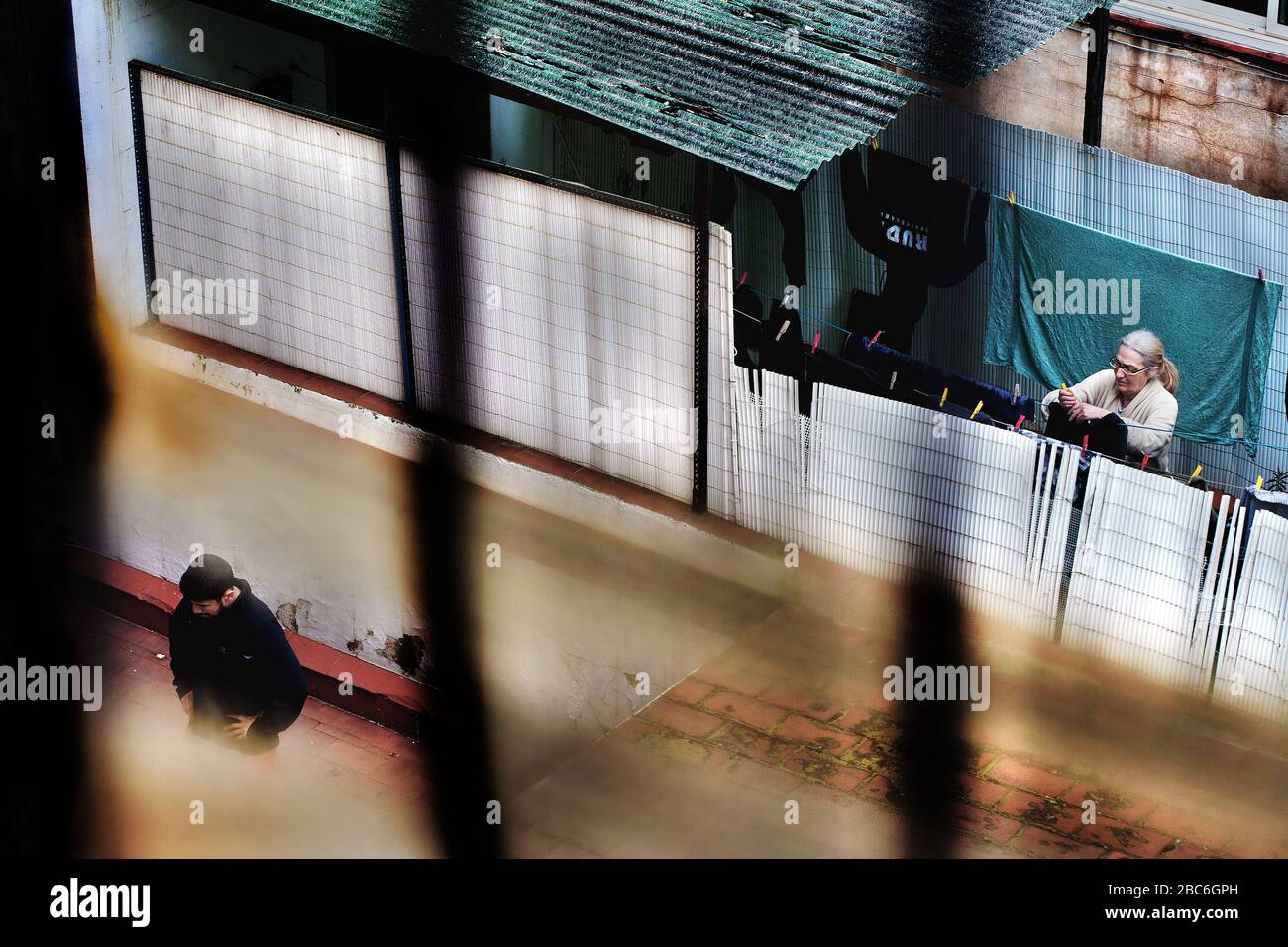 A man pauses during his exercise routine while a neighbour hangs out washing during lockdown, Barcelona Spain. Stock Photo