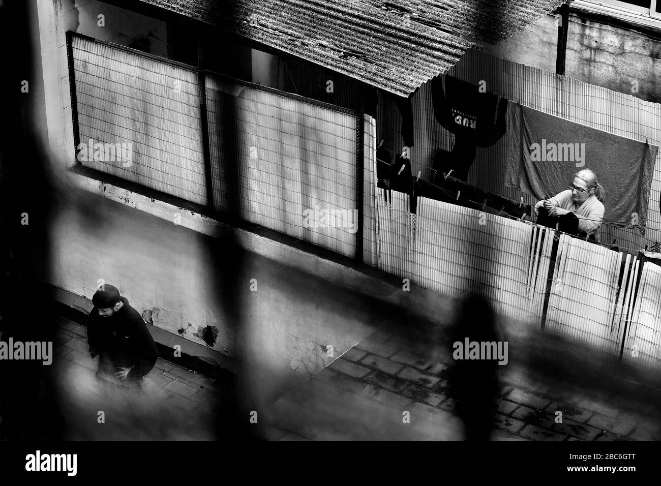 A man pauses during his exercise routine while a neighbour hangs out washing during lockdown, Barcelona Spain. Stock Photo