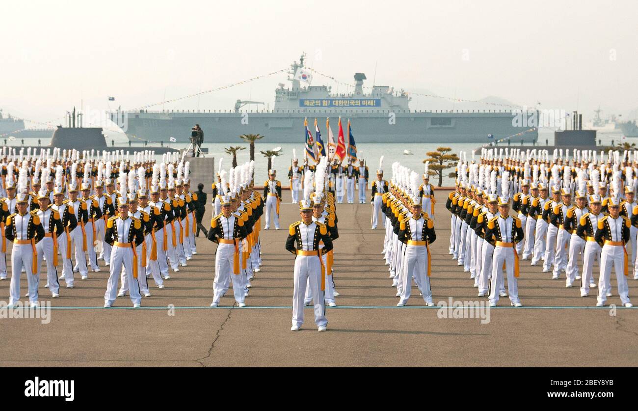 JINHAE, Republic of Korea (Feb. 22, 2013) Midshipmen at the Republic of Korea (ROK) Naval Academy stand in formation at parade rest with ROK Navy ships and submarines behind them minutes before the commencement of their graduation ceremony. Stock Photo