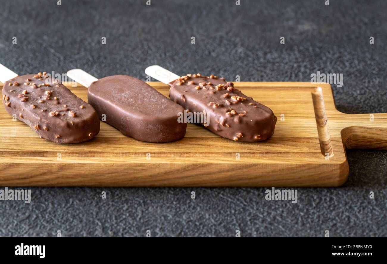 Chocolate-covered vanilla ice cream bars on the wooden board Stock Photo